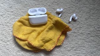 AirPods case next to a cleaning cloth and earbuds.