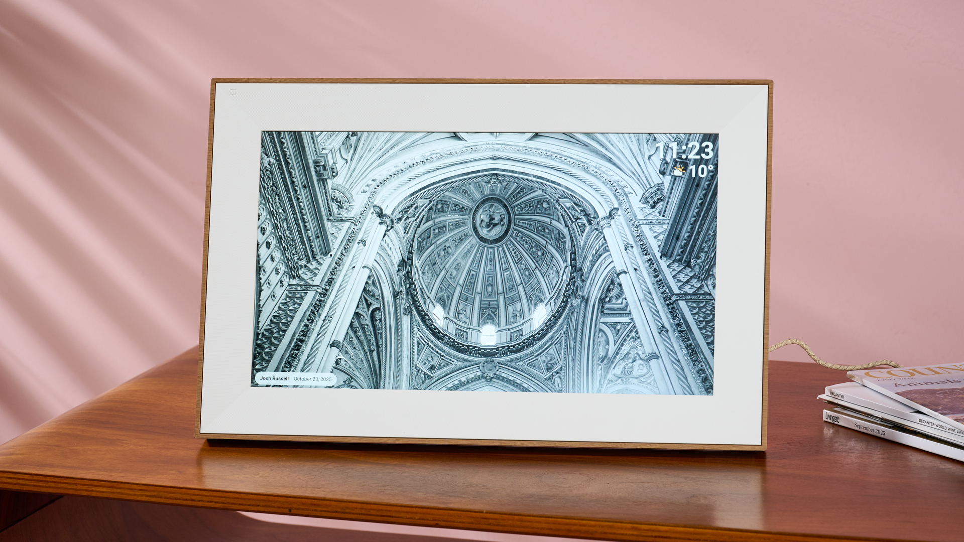 The Pexar Starlight 15.6-inch featuring a photo of an ornate cathedral ceiling in landscape orientation on a side table in front of a pink wall.