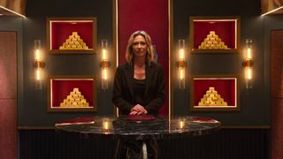 Brooke Baldwin standing in a vault with gold bars behind her.