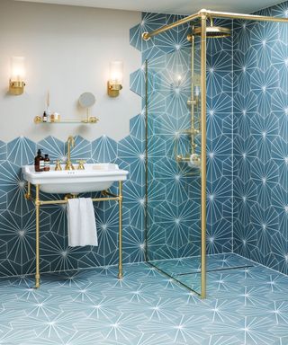 Bathroom featuring statement blue hexagonal design tiles across floor and up walls, complemented by brass fittings and fixtures