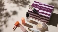 A variety of Cult Beauty products on a sheet of linen beneath dappled light.