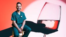 Dr Amir Khan sitting on stool in front of woman holding wine glass