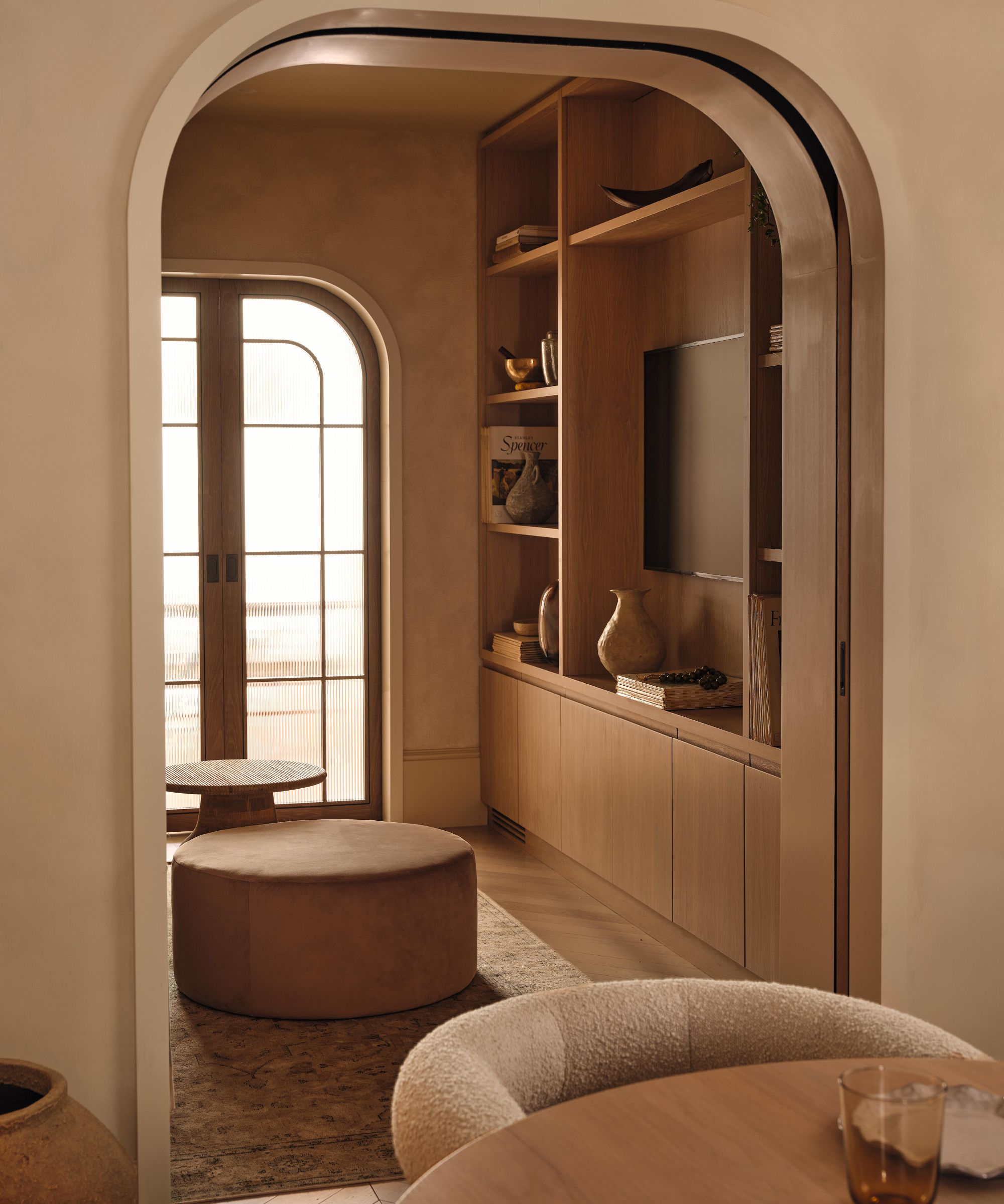 a limewashed dining room with an arched look through to a snug room