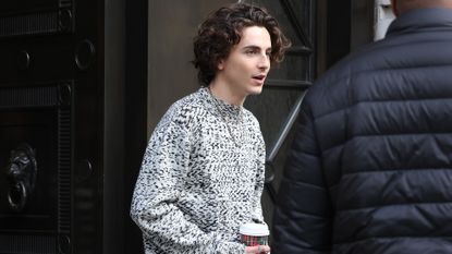 Timothée Chalamet in black leather pants and a gray sweater
