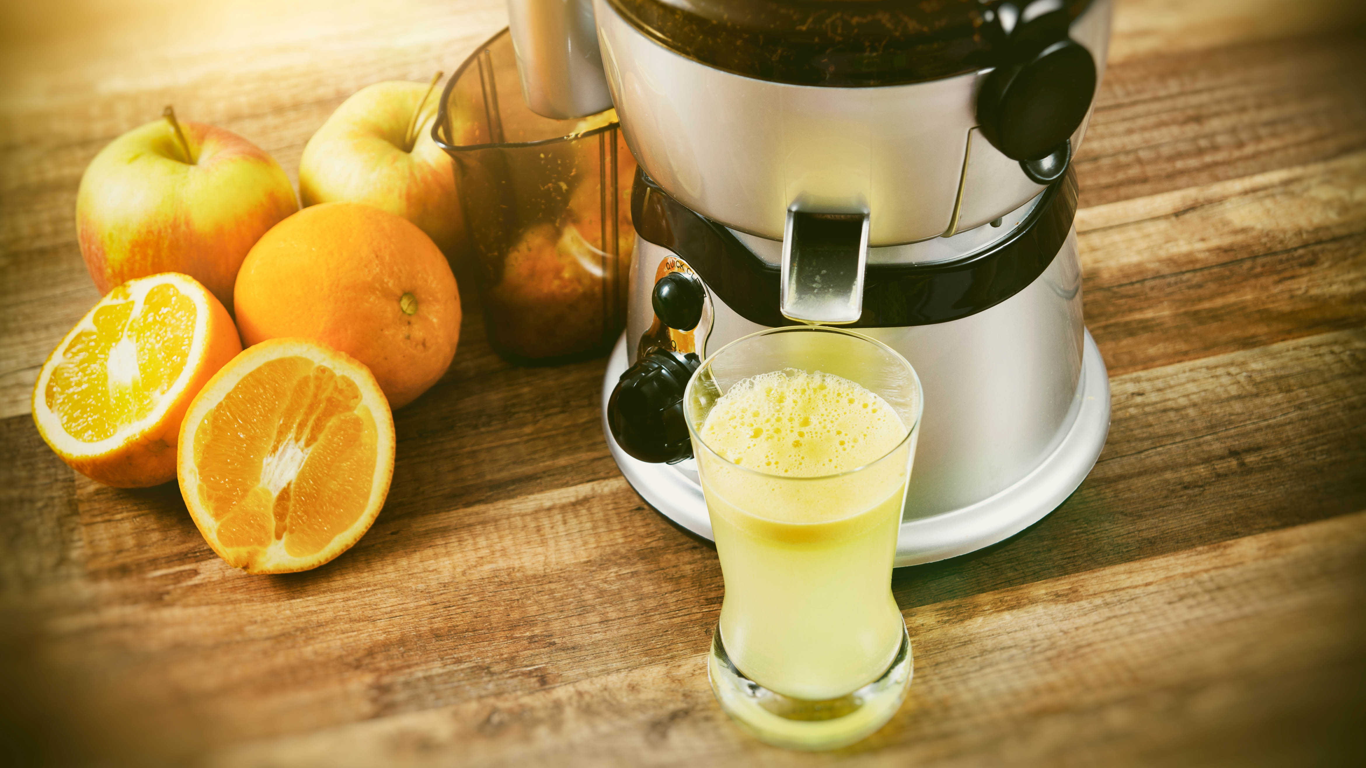 A juicer pouring out fresh apple juice on a counter