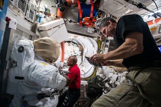 NASA astronauts Mike Hopkins (foreground) and Victor Glover configure tools inside the International Space Station's Quest airlock on Jan. 8, 2021, to prepare for two planned spacewalks.