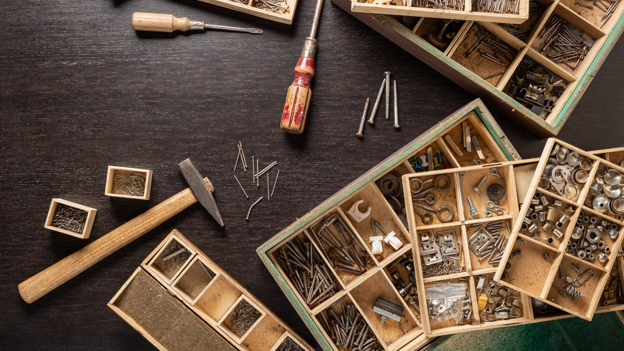 Assorted nuts bolts nails and screws ordered into wooden case on black table 