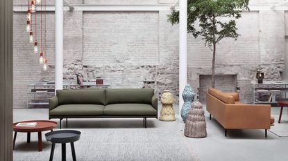 A pair of contemporary sofas in a large open plan living space with concrete flooring and brick walls