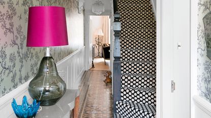 Hallway full of patterned with wallpaper, patterned floor tiles and spotty carpet on the stairs