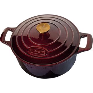 A dark purple cast iron dutch over with a brushed brass lid handle