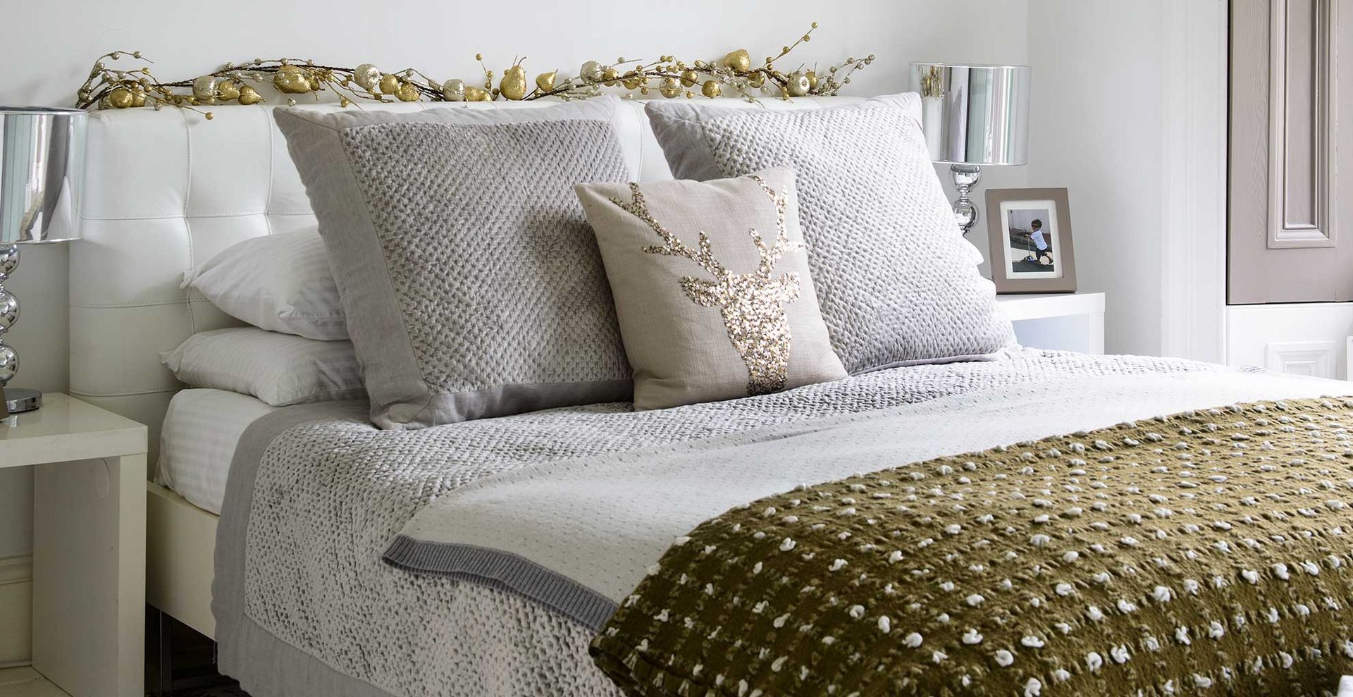 grey bedroom with subtle green Christmas garland on the headboard