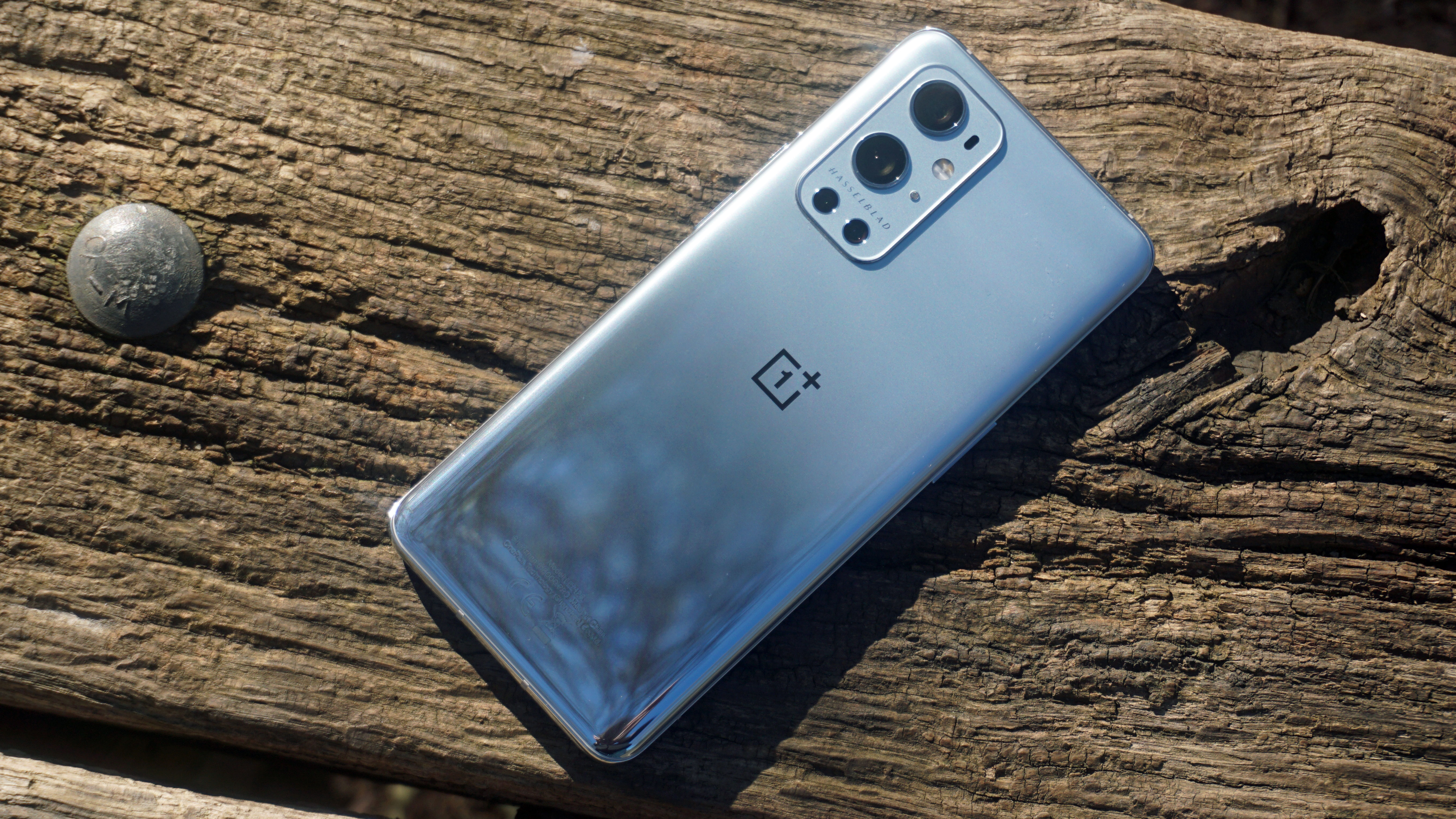 A OnePlus 9 Pro sat face down on a wooden surface