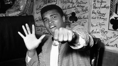 27th May 1963:Supremely confident American boxer Cassius Clay holds up five fingers in a prediction of how many rounds it will take him to knock out British boxer Henry Cooper.(Photo by Kent 