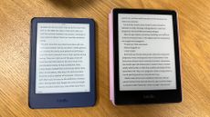 Kindle next to a Kindle Paperwhite with screens on, on a wooden desk