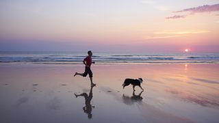 Man running on beach with dog