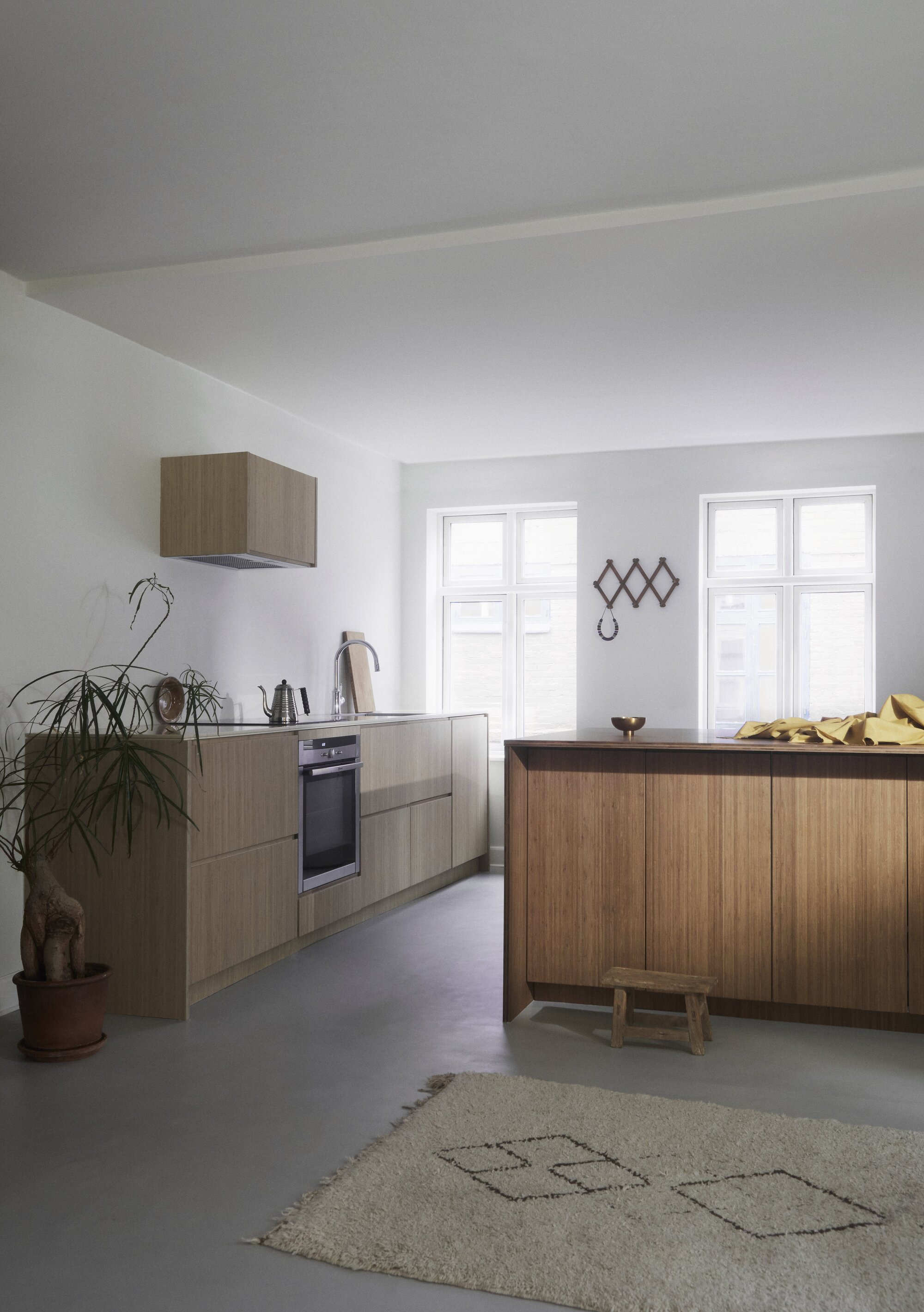 A Scandi style kitchen with wooden cabinets and a berber rug on the floor