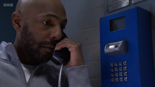 Lucas Johnson making a phone call from a prison telephone in EastEnders