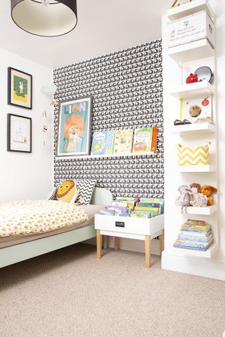 Child's bedroom with monochrome patterned feature wall and fun Scandi-style bed covers and cushions