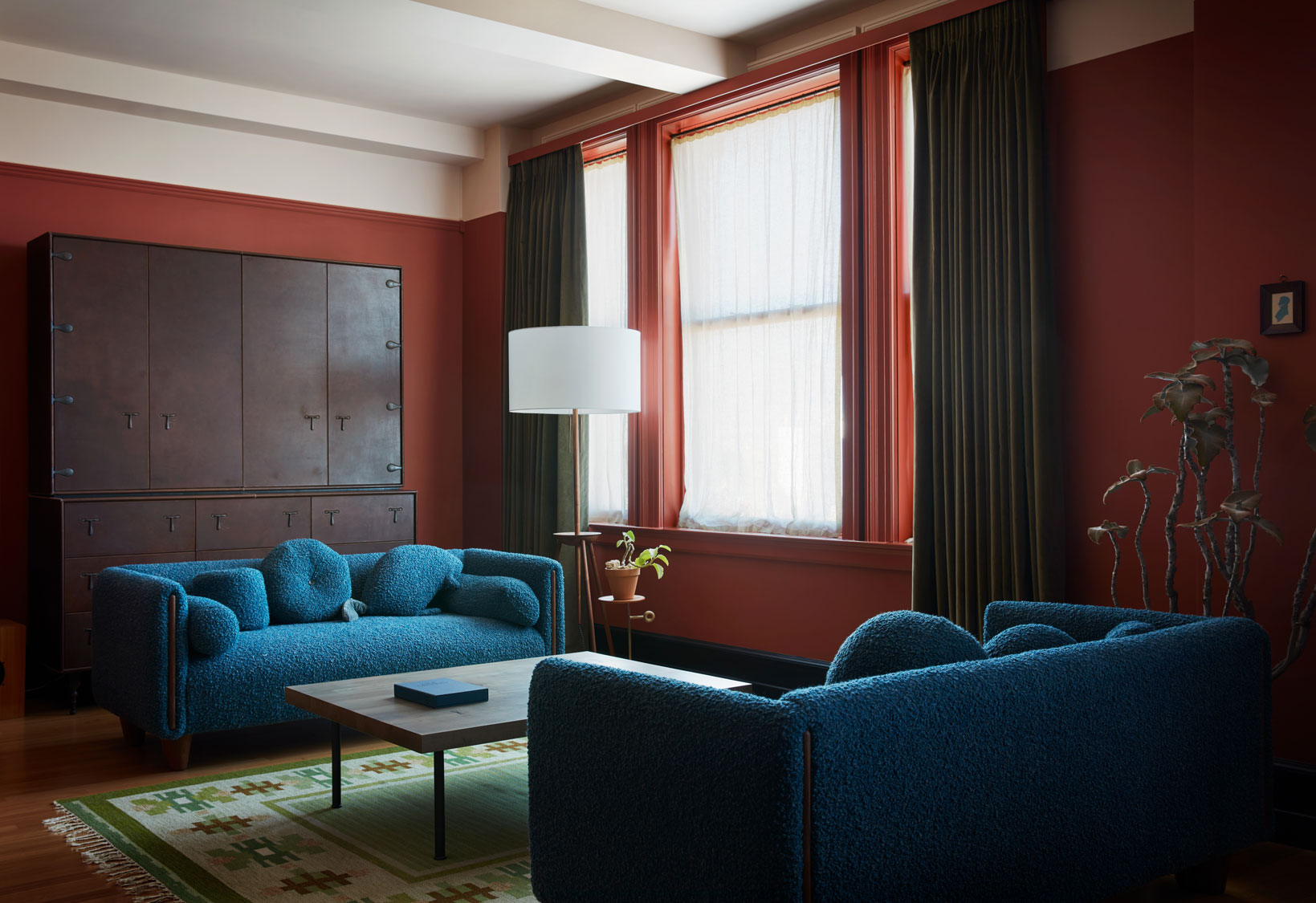 A modern glamour New York hotel boasts spherical Art Deco lighting paired with ornate walls filled with artworks and wooden cabinetry, all infused with soft pastels.