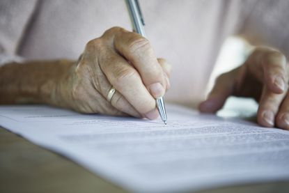 Senior woman's hand signing a document, close-up 