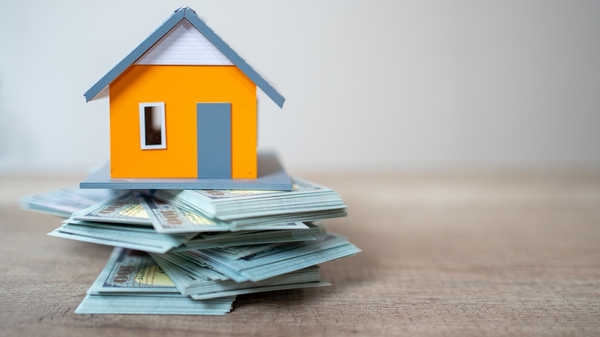 A model house sits on a stack of cash.