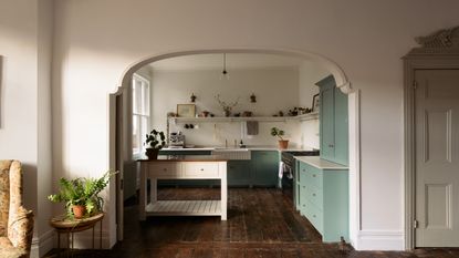 A small open plan kitchen with a small island on the left side of the kitchen and open shelving in the space. 