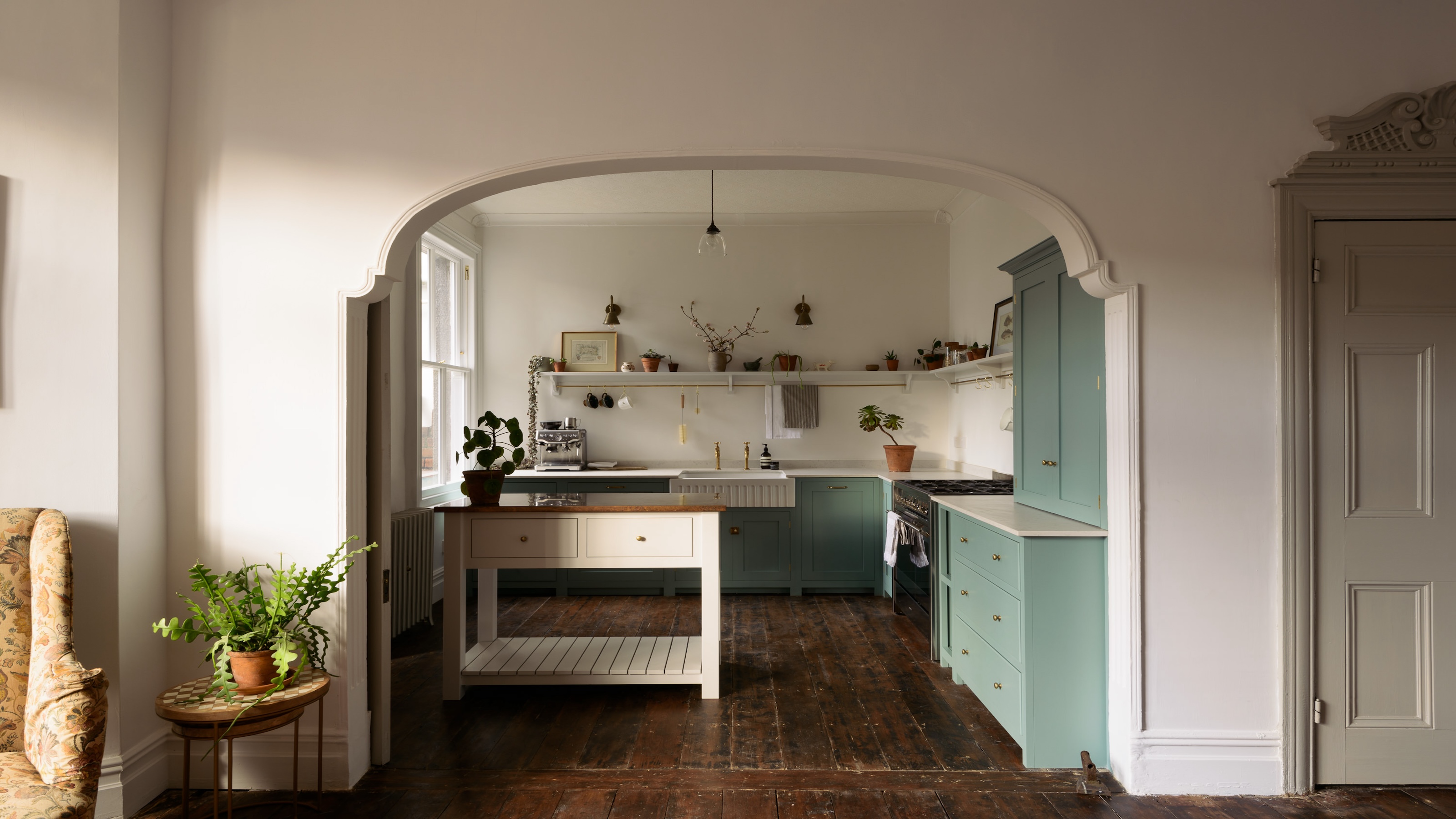 A small open plan kitchen with a small island on the left side of the kitchen and open shelving in the space. 