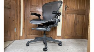 Herman Miller Aeron chair, in a hallway, surrounded with dark wood doors.