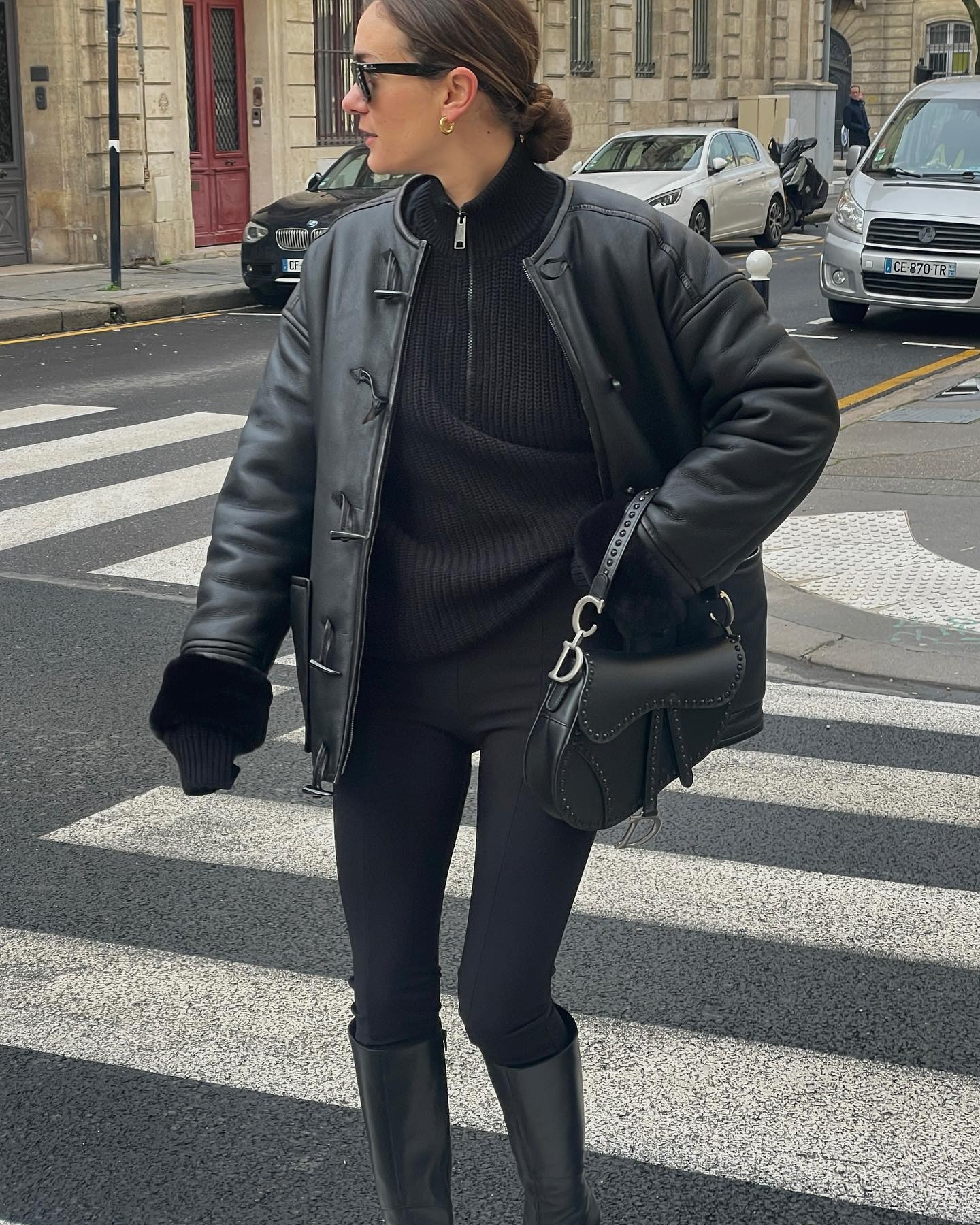 Influencer @annelauremais wears a leather toggle jacket with black leggings and knee-high boots.