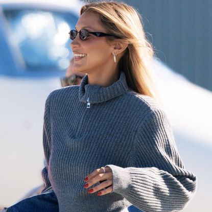 Bella Hadid arrived at the airport in her birthday outfit, featuring a quarter-zip sweater, leggings, and knee-high boots