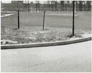 Black and white photo of curb, fence and grassy area