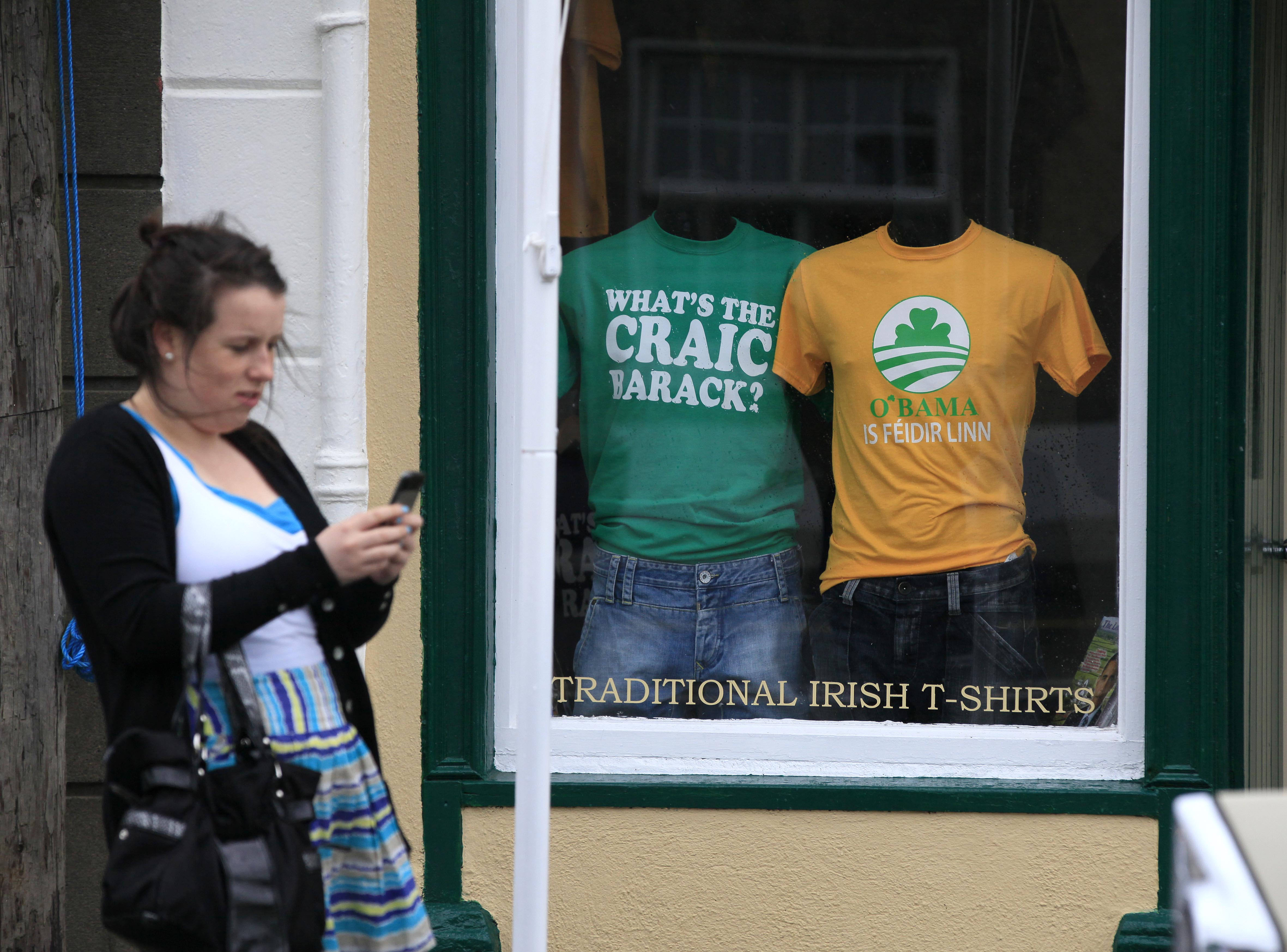 A woman walks in front of a store window in Ireland displaying Obama shirts