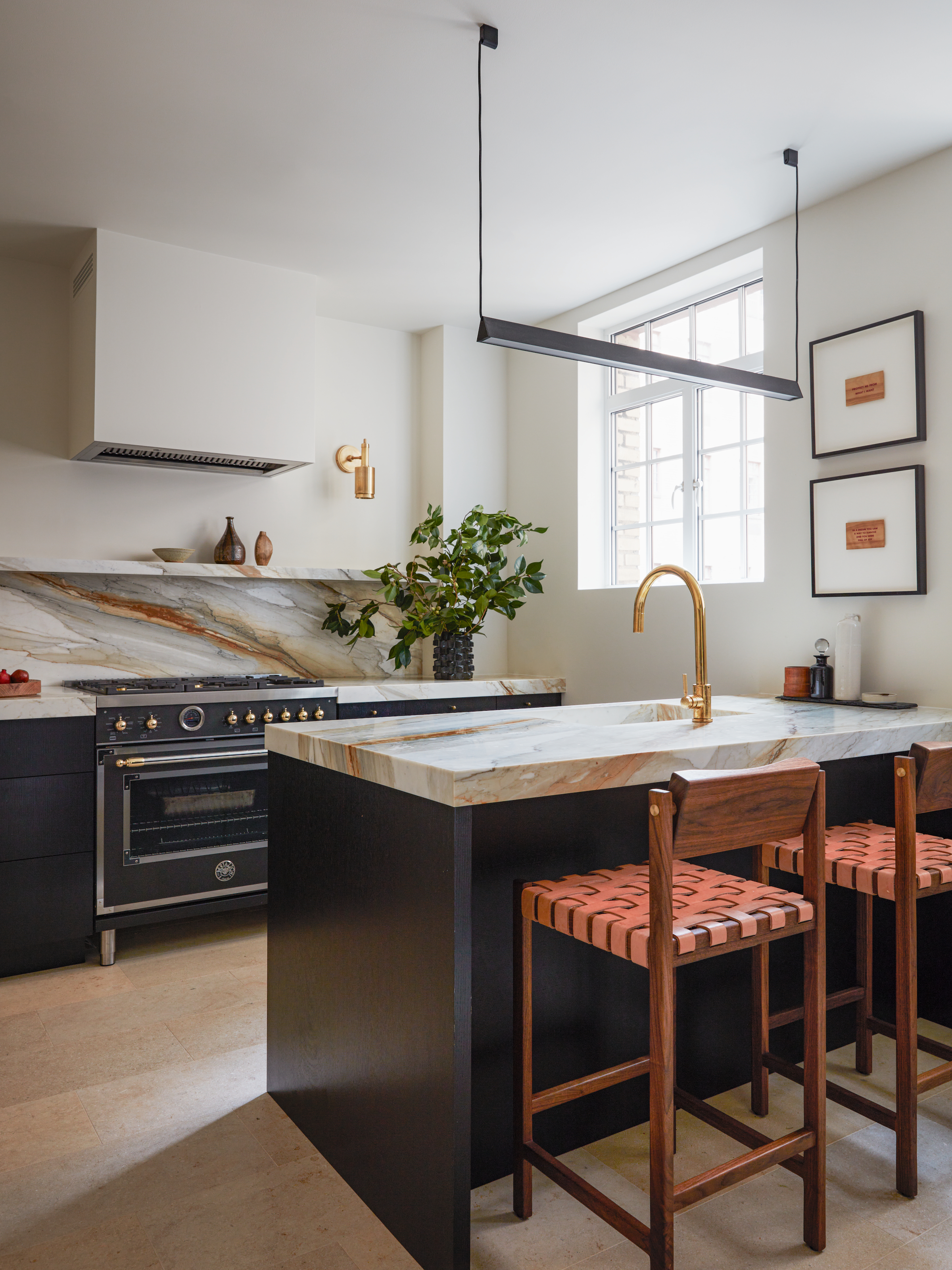 Dark blue kitchen with deep marble countertops in grey and rust, wood bar stools with woven seat