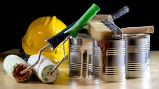 Tins of oil-based paint next to paintbrushes and rollers