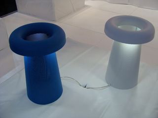 Two mushroom-like designed table lights in blue and white photographed on a grey marble surface