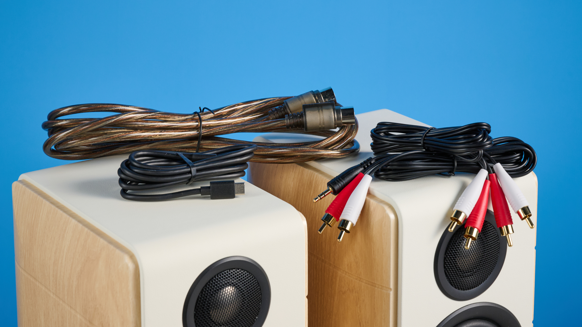 the edifier s880db mkii speakers in white and wood colorway showing the connectivity options, remote control, against a blue background