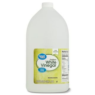 A white plastic bottle of Great Value Distilled White Vinegarwith a yellow label and a white screw cap , 128 Fl Oz