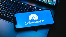 Image of the Paramount Plus logo on a mobile phone resting on a laptop