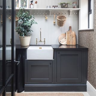Laundry room with dark grey cabinetry, Belfast sink, wall panelling and wallpaper