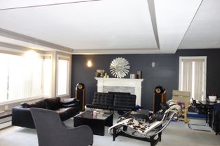 A dated living room with a dark grey feature wall and cow print lounge chair