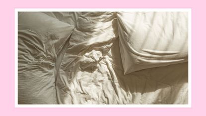 A picture of wrinkled white sheets and two pillows on a bed / in a pink template