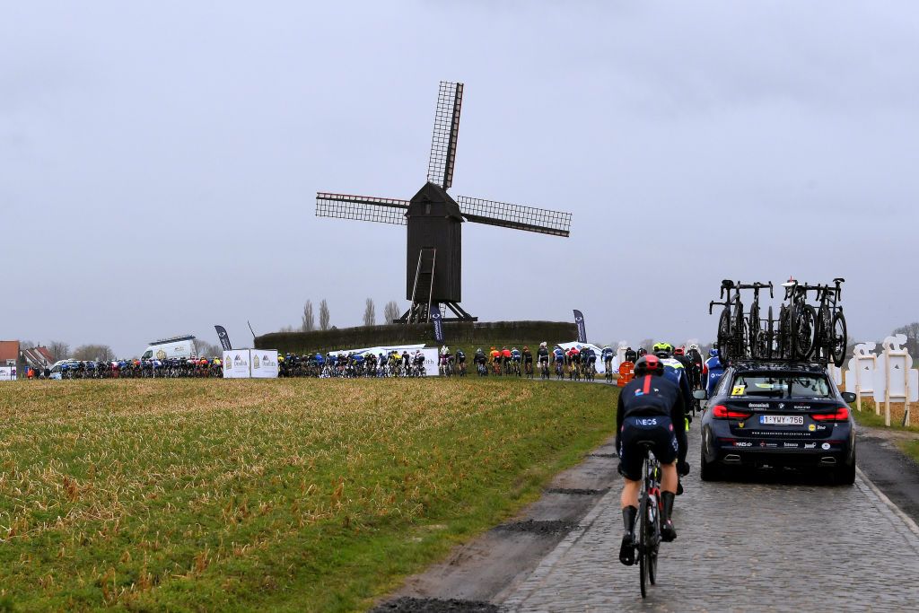 NOKERE BELGIUM MARCH 17 The peloton during the 75th Nokere Koerse Danilith Classic 2021 Mens Elite a 1955km race from Deinze to Nokere Cobblestones Windmill Rain Landscape NokereKoerse on March 17 2021 in Nokere Belgium Photo by Luc ClaessenGetty Images