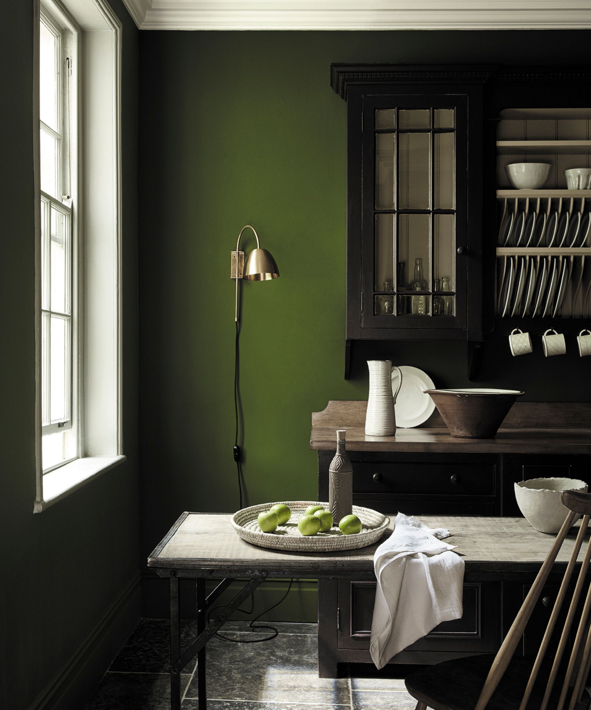 rustic dining space with dark green wall and vintage cabinet and table