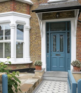 exterior of building with set off by subtle stone paving the front door and gate color gives a clue to the palette inside