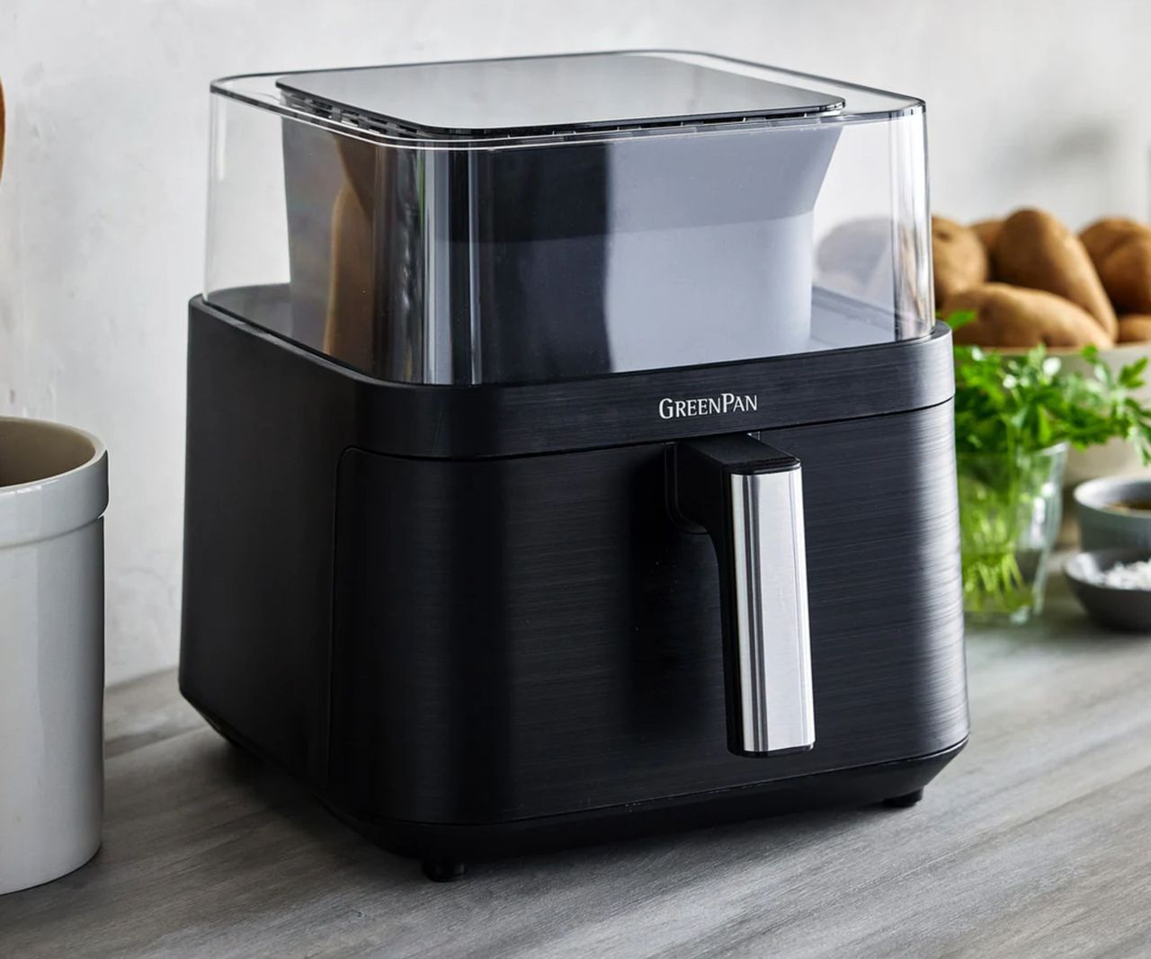GreenPan Bistro 360 Clear View Air Fryer in black on a kitchen counter with a pot of potatoes visible in the background