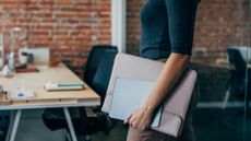 'Bring your own device' concept image showing female office worker arriving at the office with a laptop stored in a bag.