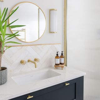 Bathroom wink above blue cabinetry with chevron tiled splashback