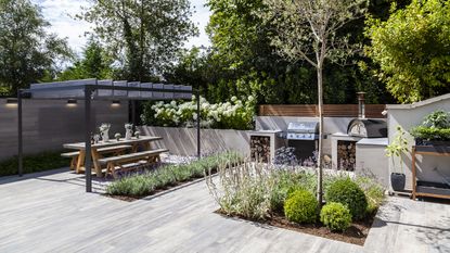 low maintenance landscaping with paving, pergola, outdoor kitchen and pizza oven