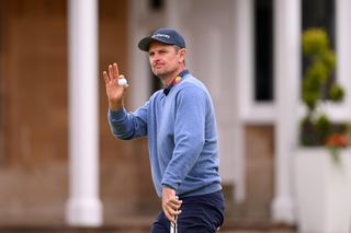 Justin Rose waves to the crowd whilst holding a Titleist golf ball