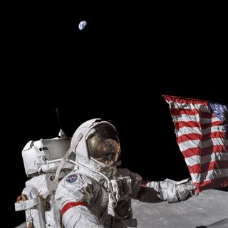 Commander Eugene Cernan with the American flag and the Earth behind him during Apollo 17.